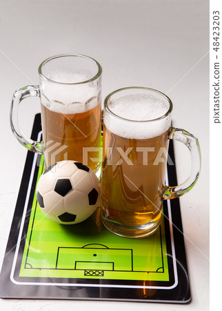 Photo on top of two mugs of frothy beer, table football, ball 48423203