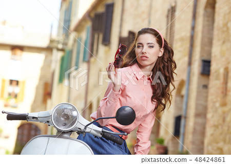 italian woman sitting on a vintage  scooter. 48424861