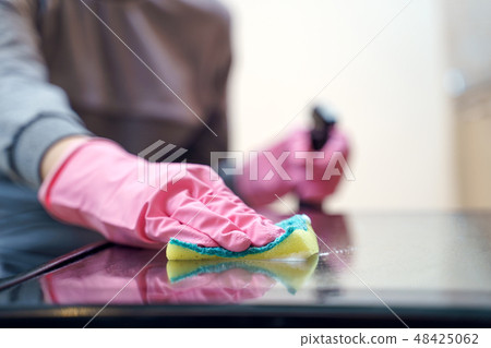 Photo of woman's hands in pink glove with sponge and spray washing oven . 48425062