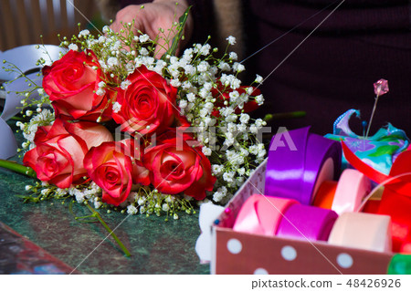 Florist makes a bouquet of red roses Florist makes a bouquet of red roses 48426926