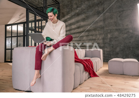 Green-haired woman wearing beige sweater working from home 48429275