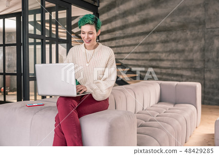 Freelance writer working on her laptop sitting on sofa at home Freelance writer working on her laptop sitting on sofa at home 48429285