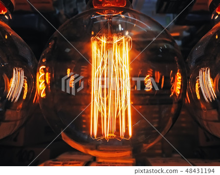 Bright glowing clear glass lamp spherical shape close up. Illumination edison retro lamp dark 48431194