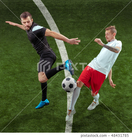 Football players tackling ball over green grass background 48431785