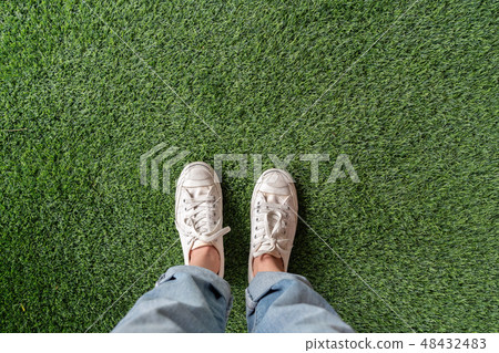 top view of female feet standing on green grass top view of female feet standing on green grass 48432483