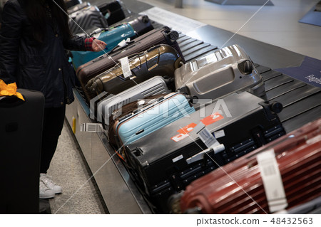 people waiting for luggage on a conveyor belt people waiting for luggage on a conveyor belt 48432563