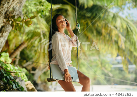 woman listen to music on beach and holding laptop woman listen to music on beach and holding laptop 48432623