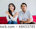 asian husband and causasian wife watch tv 48433785