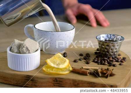 Barista pours coffee from pitcher to cup. Sprinkles halva. Hands close-up. Barista pours coffee from pitcher to cup. Sprinkles halva. Hands close-up. 48433955