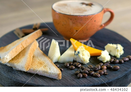 Cheese coffee with melted cheese, pieces of cheese and bread toasts on a tray. Side view. Cheese coffee with melted cheese, pieces of cheese and bread toasts on a tray. Side view. 48434102