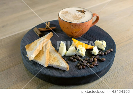 Cheese coffee with melted cheese, pieces of cheese and bread toasts on a tray. Side view. Cheese coffee with melted cheese, pieces of cheese and bread toasts on a tray. Side view. 48434103