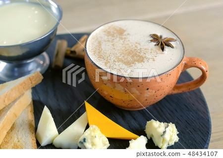 Cheese coffee with melted cheese, pieces of cheese and bread toasts on a tray. Cheese coffee with melted cheese, pieces of cheese and bread toasts on a tray. 48434107