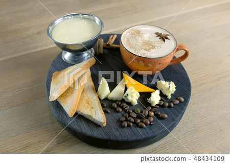 Cheese coffee with melted cheese, pieces of cheese and bread toasts on a tray. Cheese coffee with melted cheese, pieces of cheese and bread toasts on a tray. 48434109