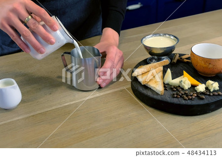 Barista makes cheese coffee, pours milk and cream to pitcher, close-up hands. Barista makes cheese coffee, pours milk and cream to pitcher, close-up hands. 48434113