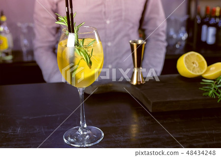 Alcohol cocktail with sparkling wine, ice and liquor , lemon and rosemary in wineglass on bar 48434248
