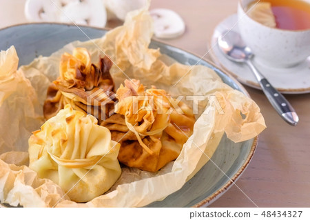 Julienne baked in dough served on a plate on baker paper with tea and butter. Close-up view. 48434327