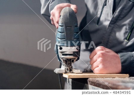 Close up of carpenter's hands working power tools for processing wood. Power Jigsaw 48434591