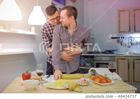 Couple of men gay flirts each other cooking a pizza together and drinking a wine. Couple of men gay flirts each other cooking a pizza together and drinking a wine. 48434737