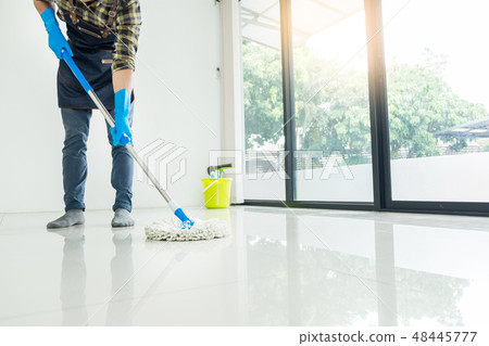 Young housekeeper cleaning floor mobbing holding mop and plastic 48445777