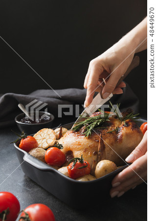 Roasted chicken with vegetable. Woman cuts chicken 48449670