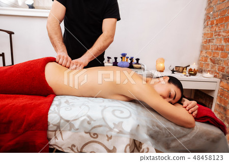 Strong fit masseur in black uniform mashing spin of lying woman 48458123