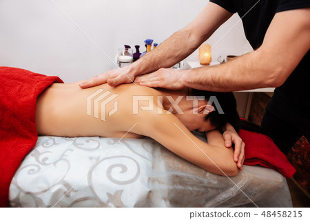 Male masseur with strong hairy hands stroking back of partly-naked client Male masseur with strong hairy hands stroking back of partly-naked client 48458215