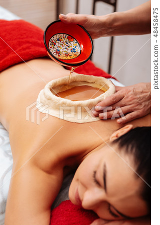 Dark-haired woman having kati vasti procedure in SPA salon Dark-haired woman having kati vasti procedure in SPA salon 48458475