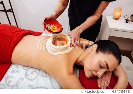Dark-haired relaxed woman experiencing Ayurveda treatment in salon Dark-haired relaxed woman experiencing Ayurveda treatment in salon 48458478