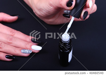 Black, white Nail art manicure. Holiday style bright Manicure with sparkles. Bottle of Nail Polish Black, white Nail art manicure. Holiday style bright Manicure with sparkles. Bottle of Nail Polish 48460540