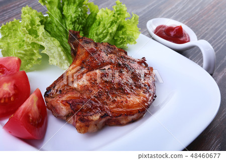 grilled pork chops with tomato, leaves lettuce and ketchup on plate. grilled pork chops with tomato, leaves lettuce and ketchup on plate. 48460677