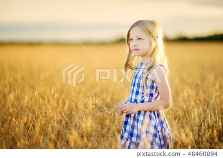 Adorable girl walking happily in wheat field on warm and sunny summer evening 48460894