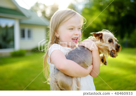 Cute little girl holding her funny yorkshire terrier dog Cute little girl holding her funny yorkshire terrier dog 48460933