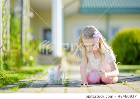 Cute little girl drawing with colorful chalks on a sidewalk. Summer activity for small kids. 48460937