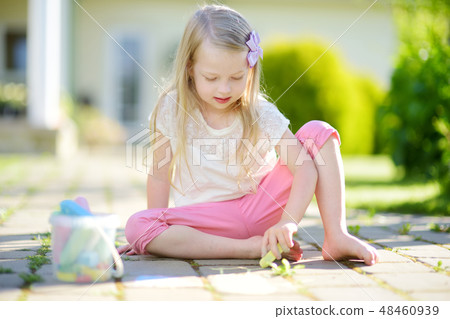 Cute little girl drawing with colorful chalks on a sidewalk. Summer activity for small kids. Cute little girl drawing with colorful chalks on a sidewalk. Summer activity for small kids. 48460939