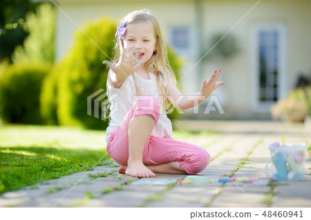 Cute little girl drawing with colorful chalks on a sidewalk. Summer activity for small kids. Cute little girl drawing with colorful chalks on a sidewalk. Summer activity for small kids. 48460941