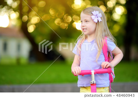 Little child learning to ride a scooter Little child learning to ride a scooter 48460943