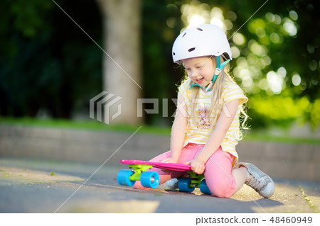 Pretty little girl learning to skateboard Pretty little girl learning to skateboard 48460949