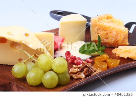 Assortment of cheese with fruits, grapes, nuts and cheese knife on a wooden serving tray. Assortment of cheese with fruits, grapes, nuts and cheese knife on a wooden serving tray. 48461326