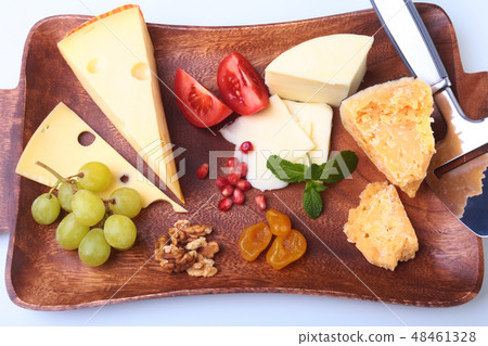 Assortment of cheese with fruits, grapes, nuts and cheese knife on a wooden serving tray. 48461328