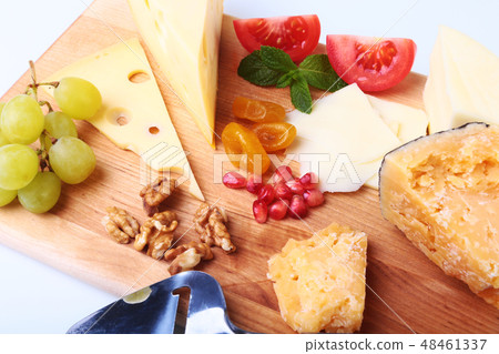 Assortment of cheese with fruits, grapes, nuts and cheese knife on a wooden serving tray. 48461337