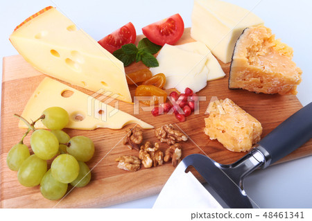 Assortment of cheese with fruits, grapes, nuts and cheese knife on a wooden serving tray. Assortment of cheese with fruits, grapes, nuts and cheese knife on a wooden serving tray. 48461341