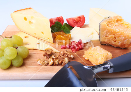Assortment of cheese with fruits, grapes, nuts and cheese knife on a wooden serving tray. Assortment of cheese with fruits, grapes, nuts and cheese knife on a wooden serving tray. 48461343