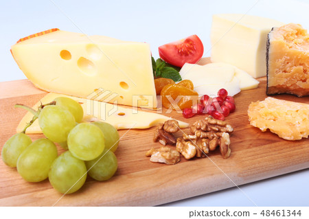 Assortment of cheese with fruits, grapes, nuts and cheese knife on a wooden serving tray. Assortment of cheese with fruits, grapes, nuts and cheese knife on a wooden serving tray. 48461344