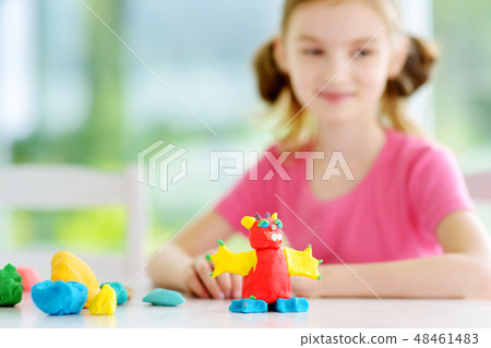 Cute little girl having fun with colorful modeling clay at a daycare. Creative kid molding at home. Cute little girl having fun with colorful modeling clay at a daycare. Creative kid molding at home. 48461483