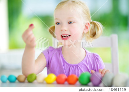 Cute little girl having fun with modeling clay at a daycare. Creative kid molding at home. Cute little girl having fun with modeling clay at a daycare. Creative kid molding at home. 48461539