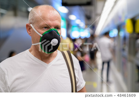 Senior man using face mask to protect from pollution smog in city 48461609