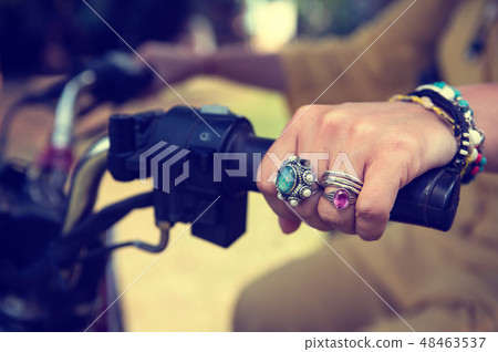 Women's hands close-up with jewelry on the handlebar of a motorcycle 48463537