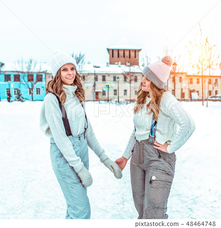 Two girlfriends girls students, in winter in the city, a public rink. In casual clothes and warm 48464748