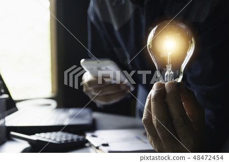 Hand of male holding a light bulb and copy space Hand of male holding a light bulb and copy space 48472454