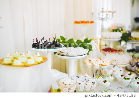 Delicious and tasty dessert table with cupcakes shots at reception closeup 48473188